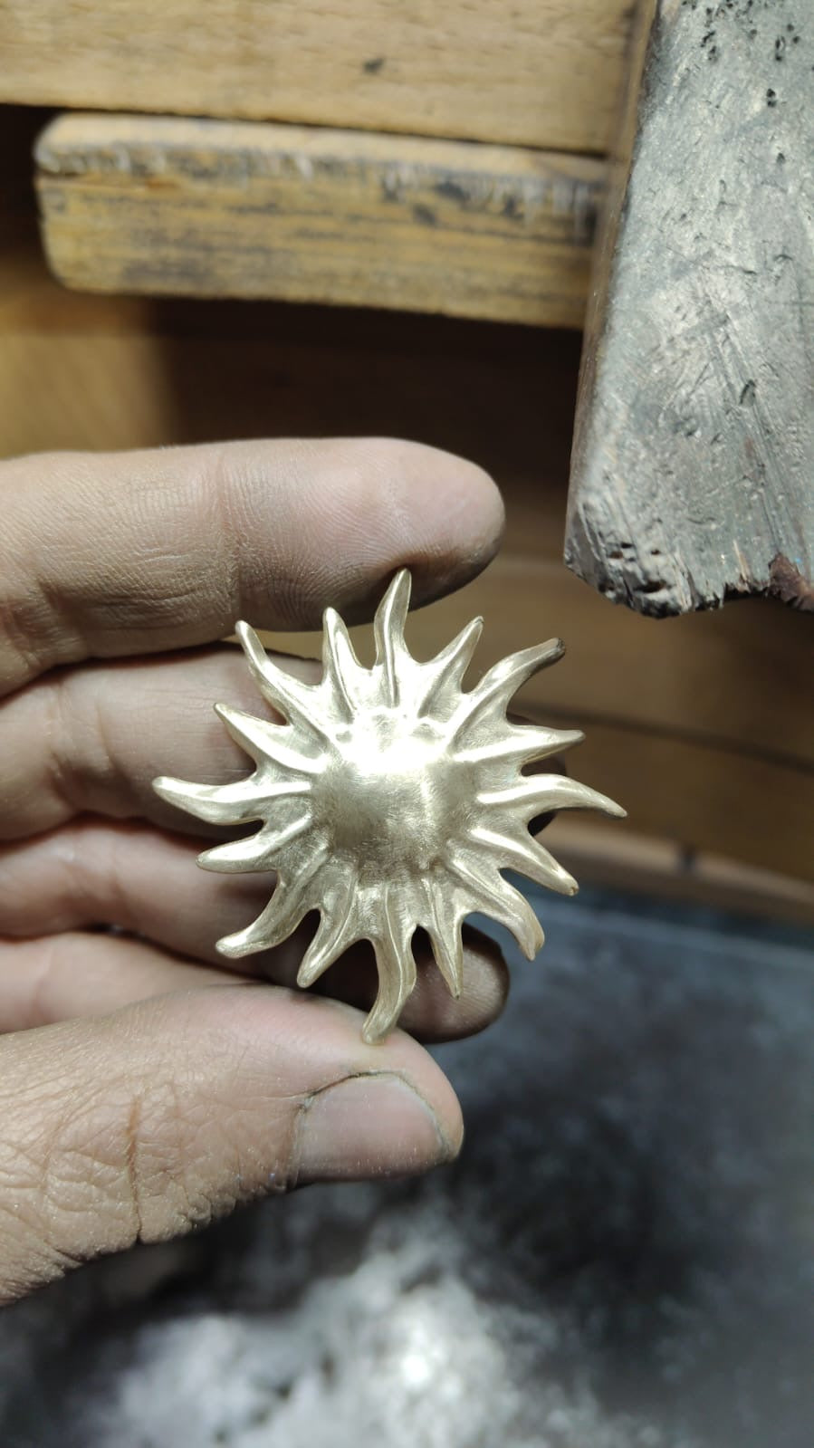 A handmade gold sun pendant before polishing