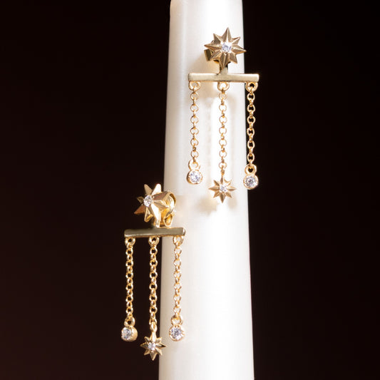 Diana Earrings in 14-karat gold: eight-point star studs with three-chain jackets ending in white stones and a small star